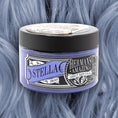 Load image into Gallery viewer, En 115 ml rund beholder med Hermans Hårfarve Stella Blue, en vegansk hårfarve, er sat på baggrund af blå hårfarve. Den udsmykkede etiket viser farvenavnet med en gammeldags designflair.
