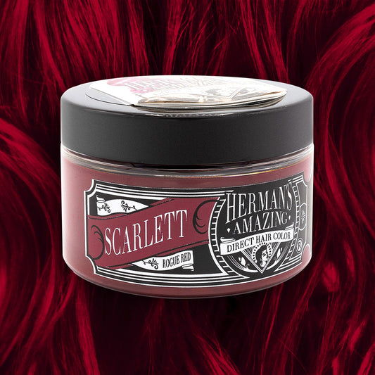En krukke med Hermans Hårfarve Scarlett Rouge (115 ml) er sat på baggrund af et livligt rødt hår. Det sorte låg står i kontrast til det rige, semi-permanente farvestof indeni, hvilket fremhæver dens fede, veganske farve.